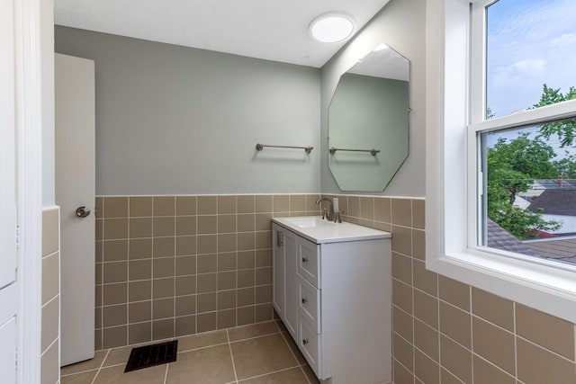 bathroom featuring tile patterned floors, tile walls, a healthy amount of sunlight, and visible vents