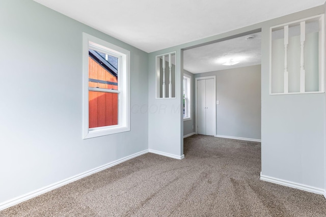 carpeted empty room with baseboards and plenty of natural light