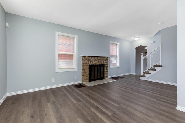 unfurnished living room with dark wood-type flooring, baseboards, visible vents, and stairway
