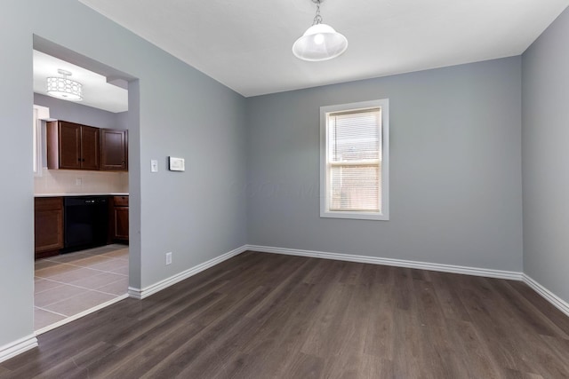 spare room with baseboards and wood finished floors