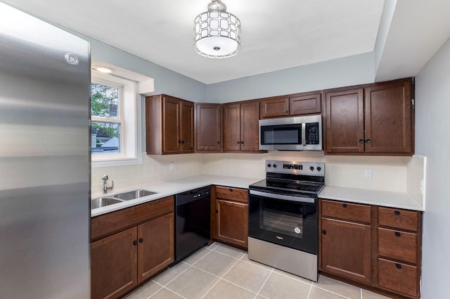 kitchen featuring decorative backsplash, light tile patterned flooring, light countertops, a sink, and appliances with stainless steel finishes