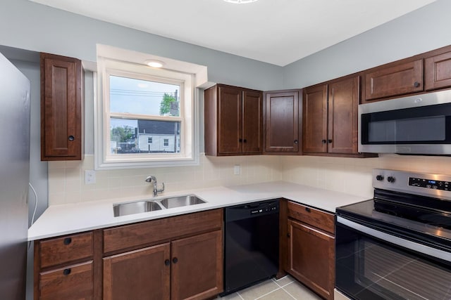kitchen featuring dark brown cabinets, appliances with stainless steel finishes, a sink, light countertops, and backsplash
