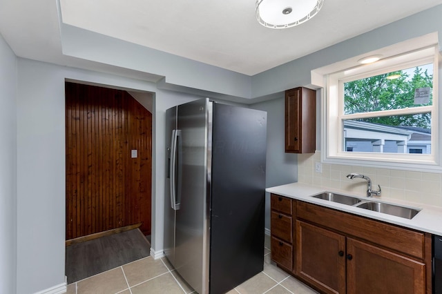 kitchen with decorative backsplash, baseboards, stainless steel refrigerator with ice dispenser, light countertops, and a sink