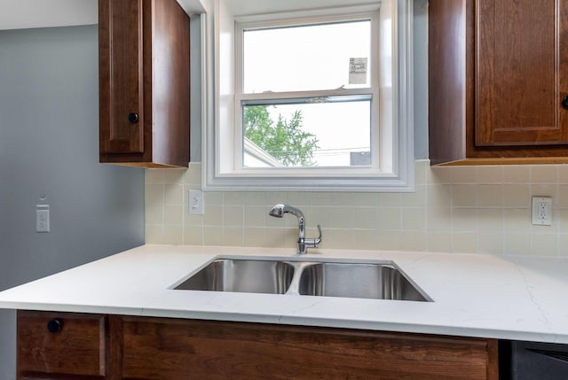 kitchen featuring a sink, light stone countertops, and tasteful backsplash