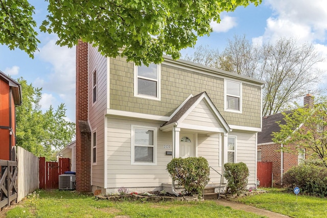 view of front of house with fence, central AC, and a front yard