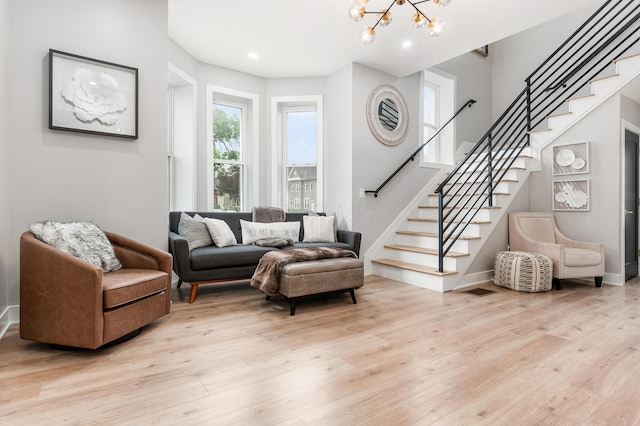 living room featuring stairway, light wood-style floors, and a chandelier