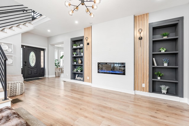 entryway with a glass covered fireplace, wood finished floors, and stairway