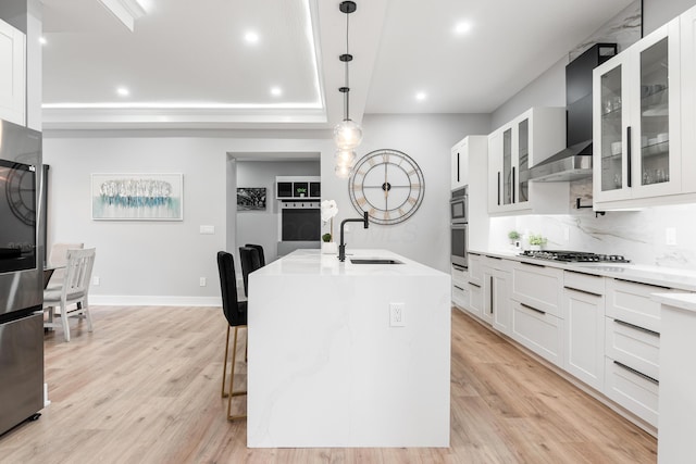 kitchen featuring a sink, an island with sink, wall chimney exhaust hood, stainless steel appliances, and recessed lighting