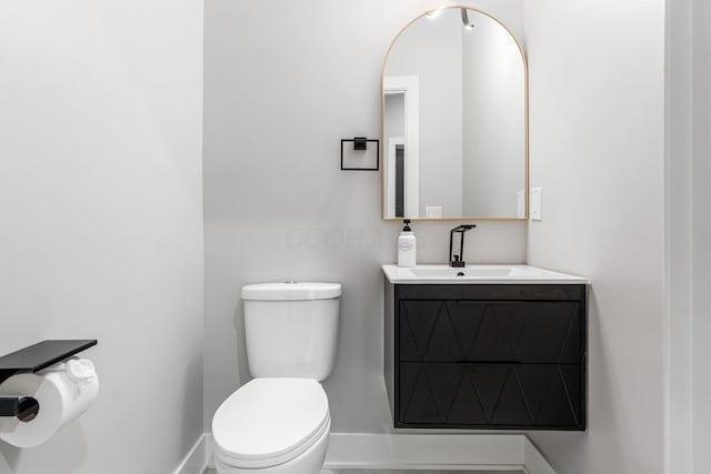 bathroom with toilet, baseboards, and vanity