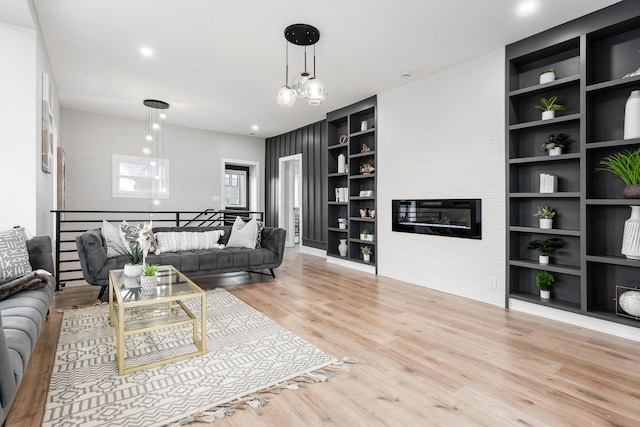 living room featuring light wood-style floors, recessed lighting, built in features, and an inviting chandelier