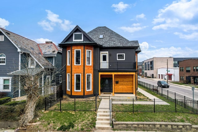 view of front of property featuring a residential view, a fenced front yard, roof with shingles, and a front lawn