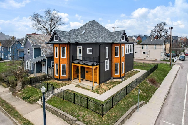 modern home with a front lawn, a fenced front yard, and a residential view
