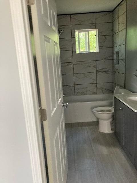 bathroom with wood finished floors, toilet, shower / bathing tub combination, and vanity