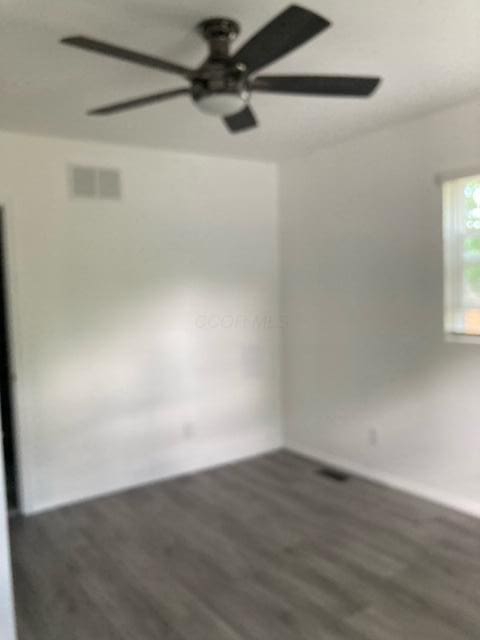 unfurnished room with visible vents, a ceiling fan, baseboards, and wood finished floors