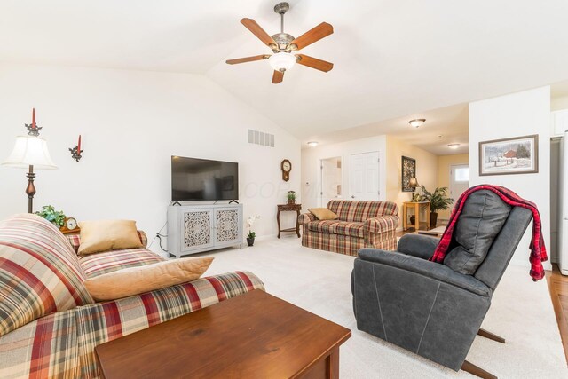 living room featuring vaulted ceiling, ceiling fan, light colored carpet, baseboards, and visible vents