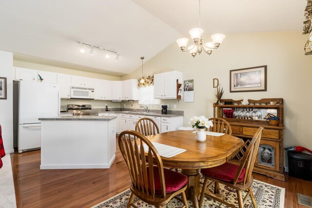 dining room with visible vents, a notable chandelier, lofted ceiling, wood finished floors, and track lighting