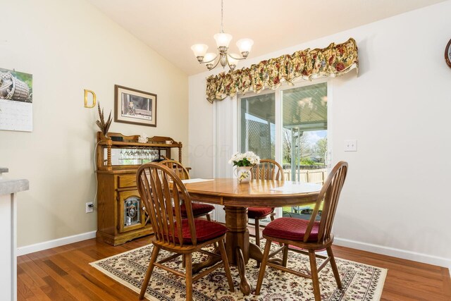 dining space with vaulted ceiling, baseboards, a notable chandelier, and wood finished floors