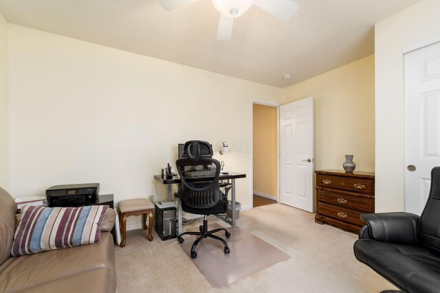 carpeted office featuring baseboards and a ceiling fan