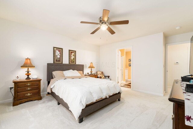 bedroom featuring connected bathroom, ceiling fan, light carpet, and baseboards