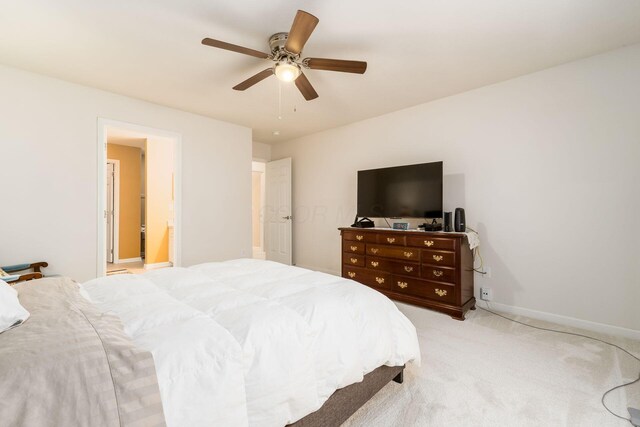bedroom featuring baseboards, a ceiling fan, light colored carpet, and ensuite bathroom