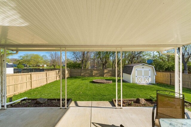 view of patio / terrace with a fenced backyard, an outbuilding, and a storage unit