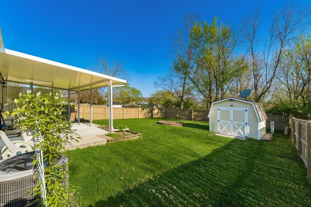 view of yard featuring a patio area, a fenced backyard, a storage unit, and an outbuilding