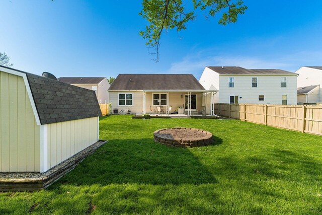rear view of property with a fenced backyard, a storage shed, a yard, an outdoor structure, and a patio
