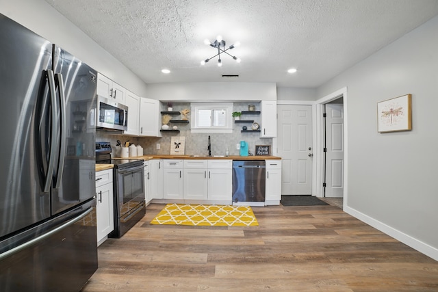1425 Mount Vernon Ave, Columbus, OH 43203 - kitchen featuring white cabinets, stainless steel appliances, open shelves, butcher block counters, and a textured ceiling