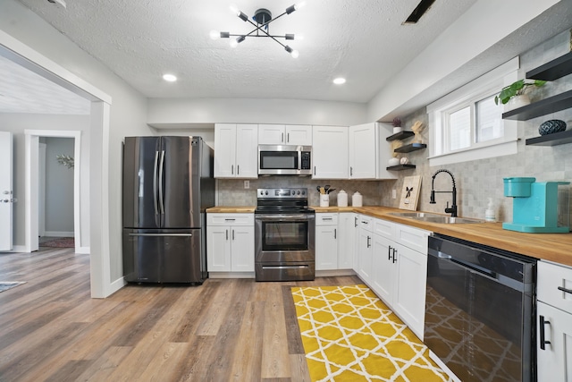 1425 Mount Vernon Ave, Columbus, OH 43203 - kitchen featuring open shelves, a sink, butcher block counters, a textured ceiling, and appliances with stainless steel finishes