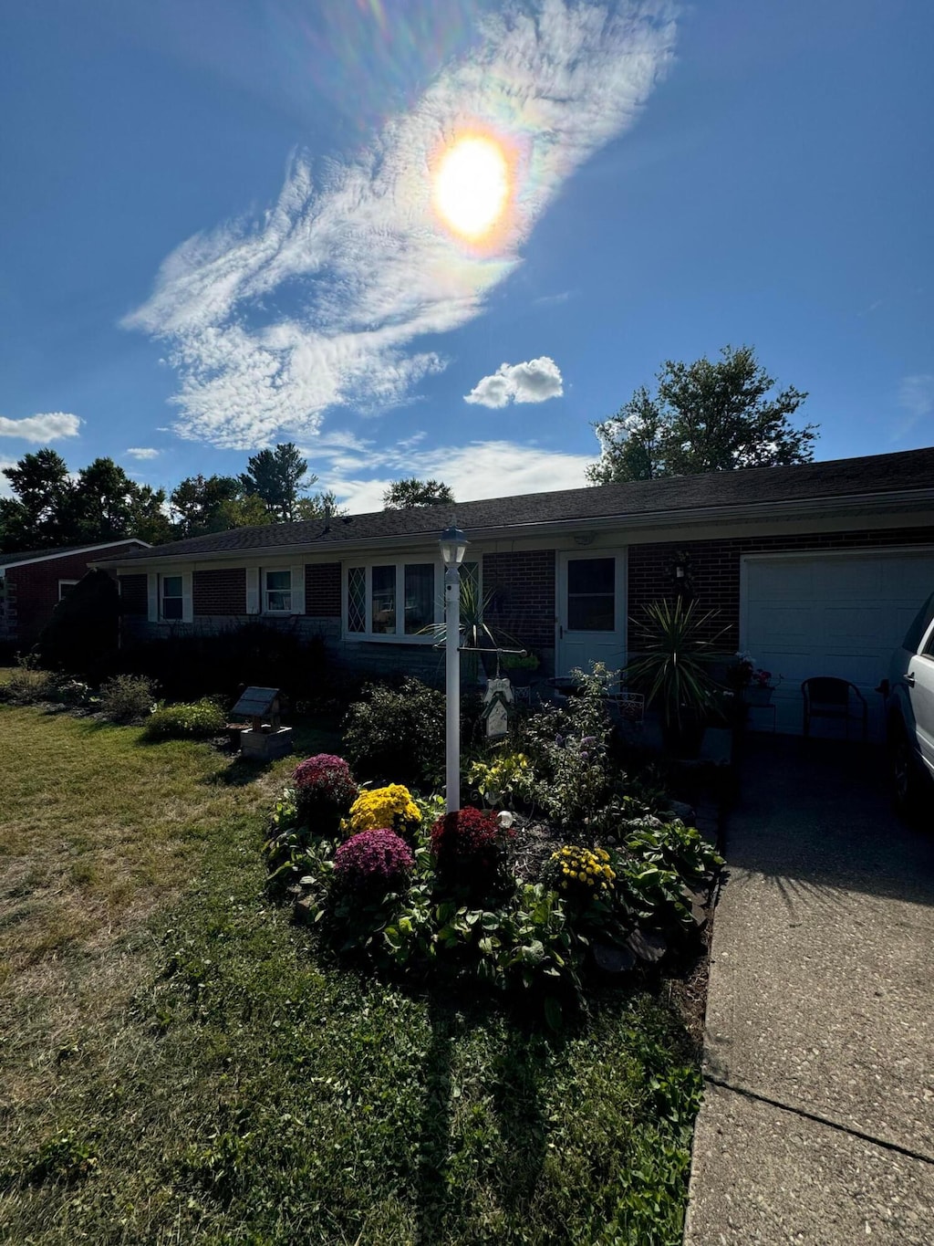 ranch-style house with an attached garage, brick siding, a front yard, and concrete driveway