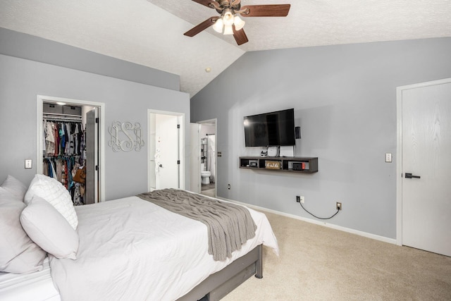carpeted bedroom with connected bathroom, baseboards, a spacious closet, a ceiling fan, and lofted ceiling