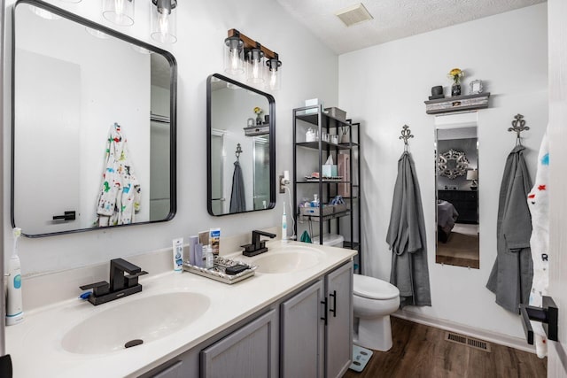 bathroom with a sink, wood finished floors, and visible vents