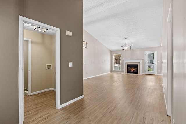 9222 Windy Creek Dr, Columbus, OH 43240 - unfurnished living room featuring vaulted ceiling, a textured ceiling, light wood finished floors, and baseboards