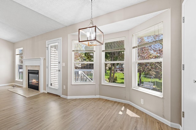 9222 Windy Creek Dr, Columbus, OH 43240 - unfurnished dining area featuring a tile fireplace, an inviting chandelier, light wood-type flooring, baseboards, and a textured ceiling