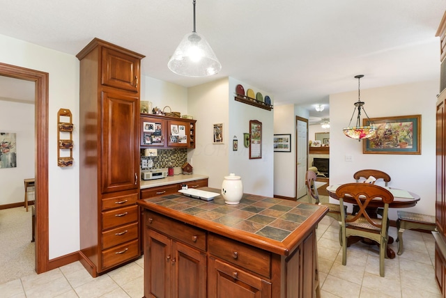 4690 Arrowhead Dr NW, Carroll, OH 43112 - kitchen with tile counters, a fireplace, backsplash, and decorative light fixtures