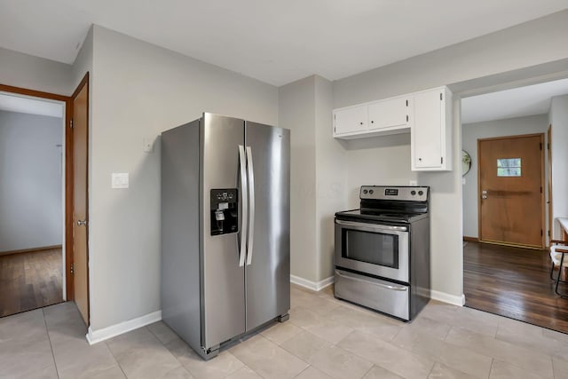 kitchen featuring appliances with stainless steel finishes, baseboards, light tile patterned flooring, and white cabinetry