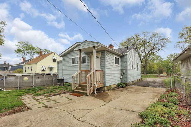 back of property featuring fence, a chimney, and driveway