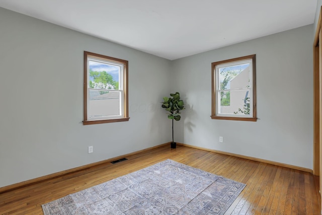 unfurnished room featuring visible vents, baseboards, and hardwood / wood-style flooring