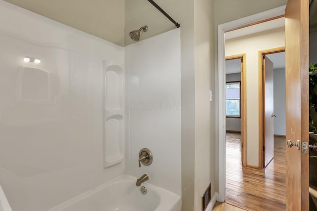 full bath with shower / tub combination, baseboards, wood finished floors, and visible vents