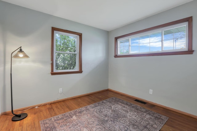 unfurnished room with baseboards, wood finished floors, and visible vents