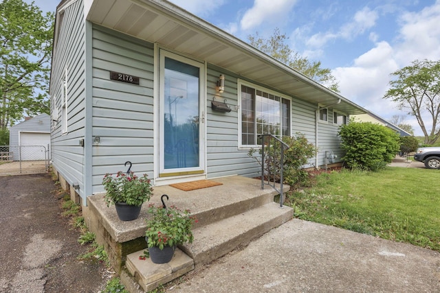 entrance to property with a lawn, a garage, and fence