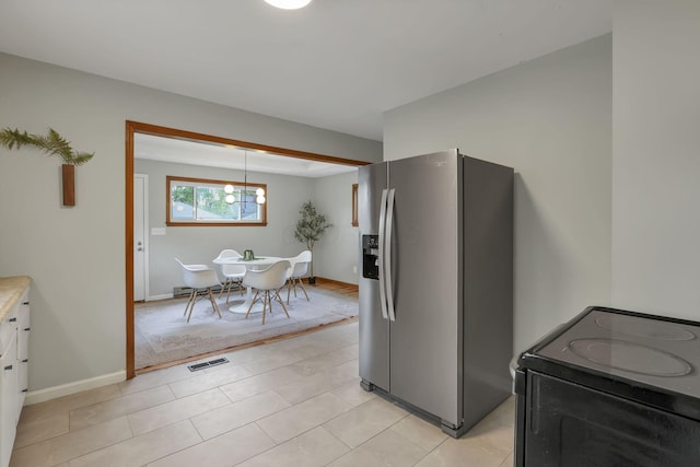 kitchen with white cabinets, light countertops, black electric range oven, stainless steel refrigerator with ice dispenser, and visible vents