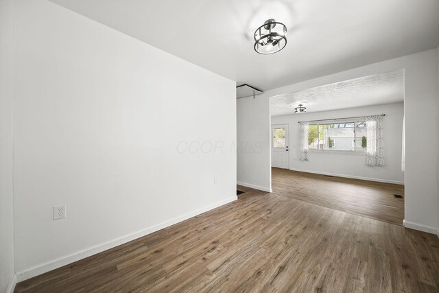 2728 Hiawatha St, Columbus, OH 43211 - unfurnished living room featuring wood finished floors, baseboards, and a chandelier