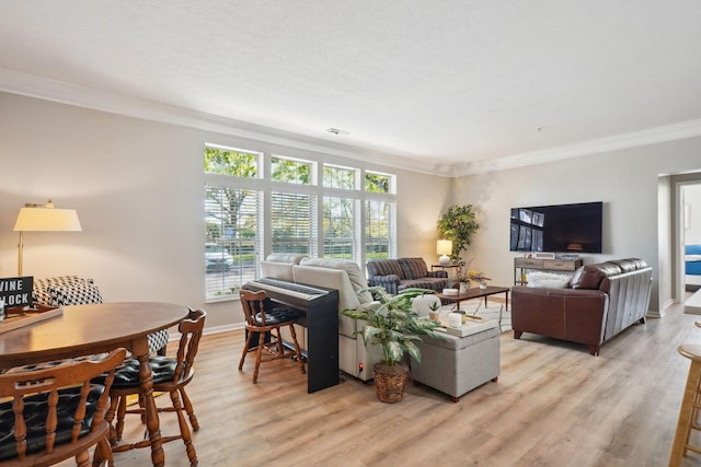living room featuring baseboards, ornamental molding, light wood finished floors, and visible vents