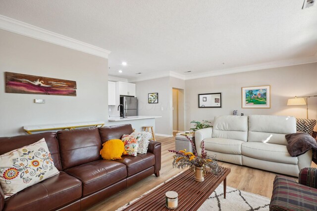 living room featuring crown molding, recessed lighting, baseboards, light wood-type flooring, and visible vents