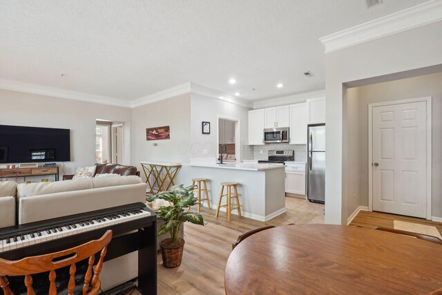 living room with recessed lighting, ornamental molding, and light wood-type flooring