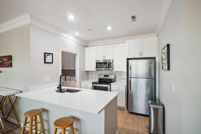 kitchen with a sink, a breakfast bar area, stainless steel appliances, tasteful backsplash, and ornamental molding