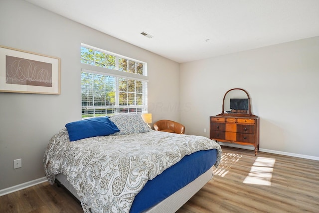 bedroom with baseboards, wood finished floors, and visible vents