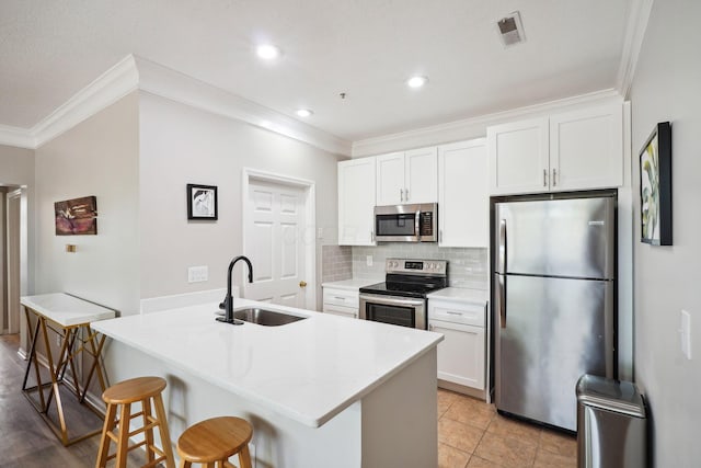 kitchen with visible vents, ornamental molding, a breakfast bar, a sink, and appliances with stainless steel finishes