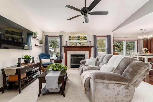 living area with a fireplace, lofted ceiling, light carpet, and ceiling fan with notable chandelier